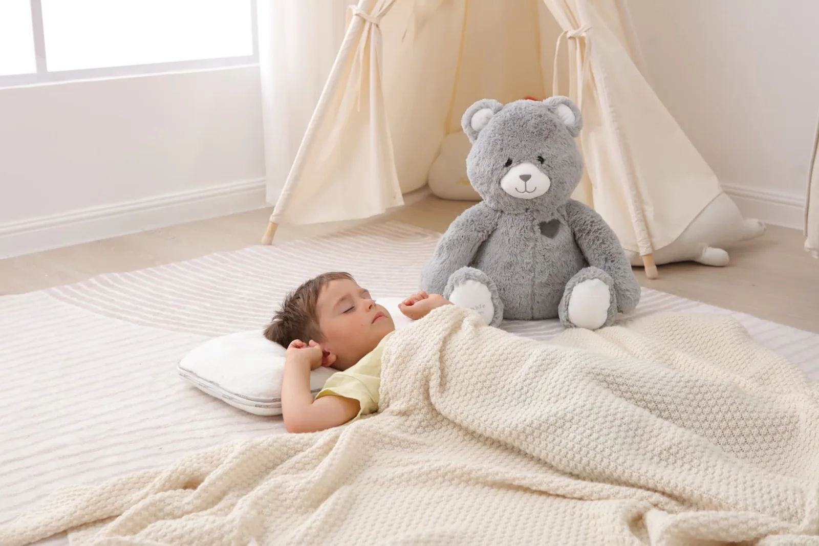 Child cuddling the grey Jumble Bear weighted plush in bed at bedtime